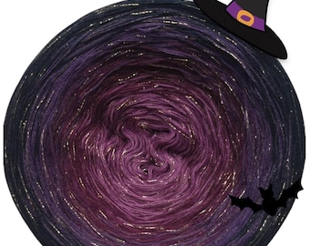 May include: A circular cake of yarn featuring a gradient colour transition from deep black at the outer edges to a vibrant purple in the centre, interwoven with metallic gold threads. A black witch hat and three small black bat silhouettes are present.