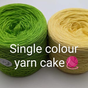 May include: Two yarn cakes, one in a vibrant lime green and the other a soft yellow, are shown. The text "Single colour yarn cake" is displayed. A pink and white yarn ball graphic is also present.