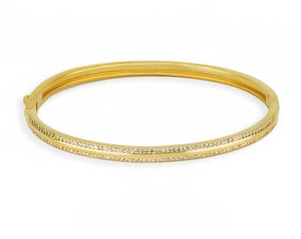 Puede incluir: Un brazalete de oro con una doble fila de piedras brillantes transparentes.