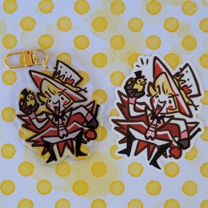 May include: A red and white cartoon character with a top hat and a red cape holding a small yellow bird. The character is on a white background with yellow polka dots. The character is a charm or keychain.