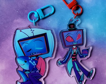 Puede incluir: Dos llaveros de personajes de dibujos animados coloridos. El primer llavero presenta un personaje de televisión azul y morado que sostiene un tiburón azul. El segundo llavero presenta un personaje de televisión morado con ojos rojos y un sombrero de copa que sostiene un cartel que dice "F*ck Blaster".
