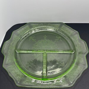 May include: A vintage, light green, divided serving plate. The plate has a scalloped edge and is divided into three sections. Intricate floral and scrollwork patterns decorate the rim and center. The plate is made of glass.