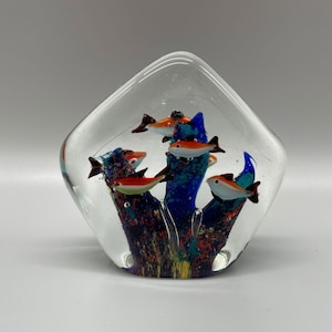 Pode incluir: Um peso de papel de vidro com um recife de coral azul, verde e laranja e peixes laranja e vermelhos dentro.