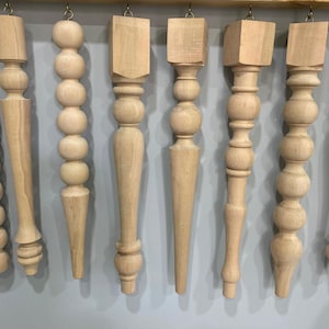 May include: Eight wooden table legs with different styles and designs. Some legs have a beaded design, while others have a more traditional turned style. All legs are unfinished and ready to be stained or painted.
