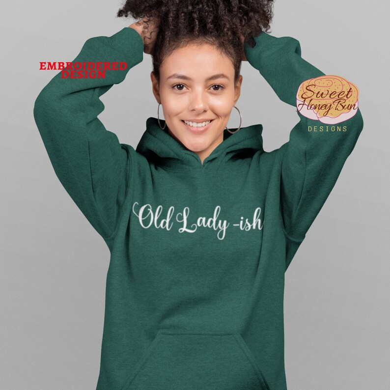 May include: A dark green hooded sweatshirt with the text "Old Lady-ish" in white cursive lettering.
