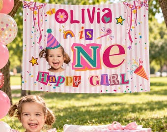 May include: A birthday party backdrop featuring a light pink and white striped pattern with the text Olivia is ONE Happy Girl, colorful confetti, stars, and a photo of a child wearing a party hat. A large rose gold number one balloon is visible.
