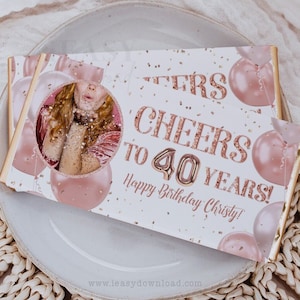 Op de afbeelding: Een witte kaart met gouden glitter en roze ballonnen. De kaart zegt "Cheers to 40 Years! Happy Birthday Christy!" met een foto van een vrouw in de hoek.