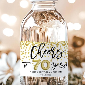 Puede incluir: Una botella de agua blanca con una etiqueta dorada y blanca que dice "Cheers to 70 Years! Happy Birthday Jennifer 08.18.2020".