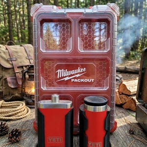 May include: Red and black YETI flask and tumbler with a red Milwaukee PACKOUT storage container. The flask and tumbler are in black holders. The storage container has a clear top and the Milwaukee logo.