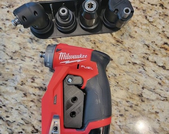 Puede incluir: Un taladro de ángulo recto Milwaukee FUEL rojo y negro con un mango de plástico negro y un accesorio de plástico negro. El taladro está en una bandeja de plástico negro con cuatro accesorios diferentes.