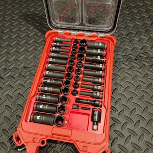 Könnte beinhalten: Ein rotes und schwarzes Milwaukee Packout Steckschlüsselsatz mit einem transparenten Deckel. Das Set enthält eine Vielzahl schwarzer Steckschlüssel mit roten Markierungen, von 6,35 mm bis 19,05 mm. Der Koffer ist geöffnet und zeigt die geordnete Anordnung der Werkzeuge.