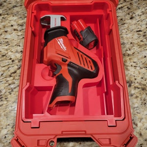 May include: A red Milwaukee reciprocating saw with a black handle and a red battery in a red plastic carrying case.