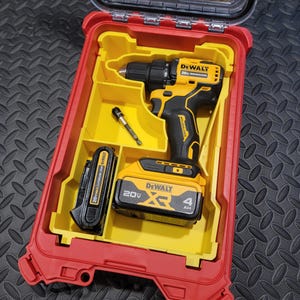 May include: A red and yellow DeWalt tool case with a clear lid, containing a yellow and black cordless drill, a battery, and a drill bit. The drill and battery have the DeWalt logo and 20V MAX XR branding.