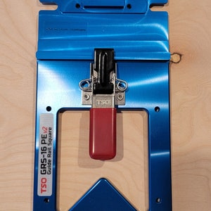 May include: A blue metal guide rail square with a red and black clamp. The square is labeled "TSO GRS-16 PE v2 Guide Rail Square".