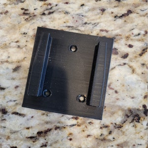 May include: Black plastic wall mount with two slots and four screw holes.