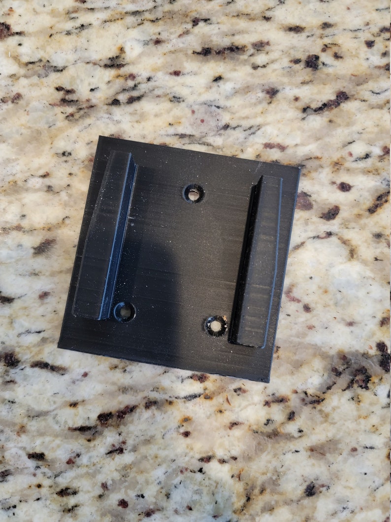May include: Black plastic wall mount with two slots and four screw holes.