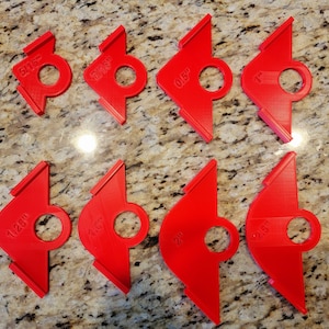 May include: Set of ten red plastic tile spacers in various sizes, ranging from 5/16 inch to 2.5 inches. Each spacer has a circular hole in the center.