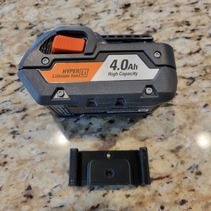 May include: A black and orange power tool battery with the text "HYPER Li Lithium Ion 4.0Ah High Capacity" on the side. A black plastic mounting bracket is also shown.