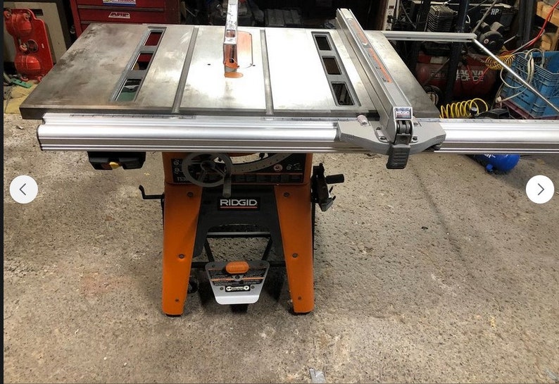 Pode incluir: Uma serra de mesa Ridgid com uma mesa de metal e uma base laranja. A serra tem uma cerca e uma r&eacute;gua de esquadria.