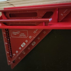 May include: Red Milwaukee trim square with markings for 15, 25, 35, 45, 55, 65, and 75 degrees. The square also has a smaller 5-degree angle.