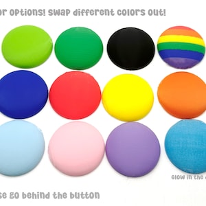 May include: A collection of colorful, round objects in various shades, including green, blue, red, yellow, orange, pink, purple, and black. One is a rainbow pattern, and another glows in the dark. Text reads "color options! swap different colors out!" and "These go behind the button."