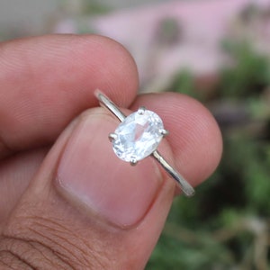 May include: A silver ring with a clear oval-shaped gemstone.