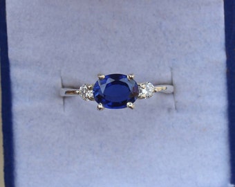 May include: A silver ring with a large oval blue sapphire and two smaller round diamonds on either side.