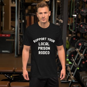 Könnte beinhalten: Ein schwarzes T-Shirt mit weißem Text, der "Support Your Local Prison Rodeo" lautet.