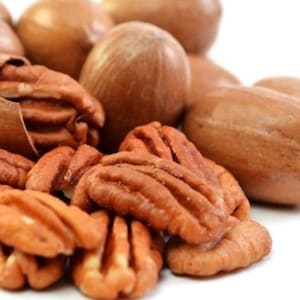 Puede incluir: Primer plano de nueces de pacana, algunas todav&iacute;a en sus c&aacute;scaras y otras descascaradas. Las pacanas son de color marr&oacute;n claro y tienen una textura ligeramente rugosa.