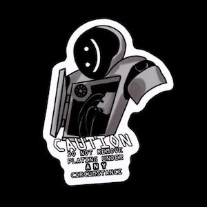 May include: Black and white sticker featuring a robot-like figure with a smiling face. The figure has a box-like body with the text "CAUTION DO NOT REMOVE PLATING UNDER ANY CIRCUMSTANCE". The sticker is on a black background.