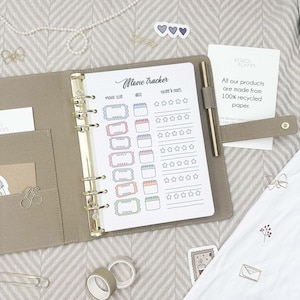 May include: A white planner page with a movie tracker section. The page has a title "Movie Tracker" and includes sections for movie title, date, rating, and notes. The page is decorated with colourful stickers and stars.
