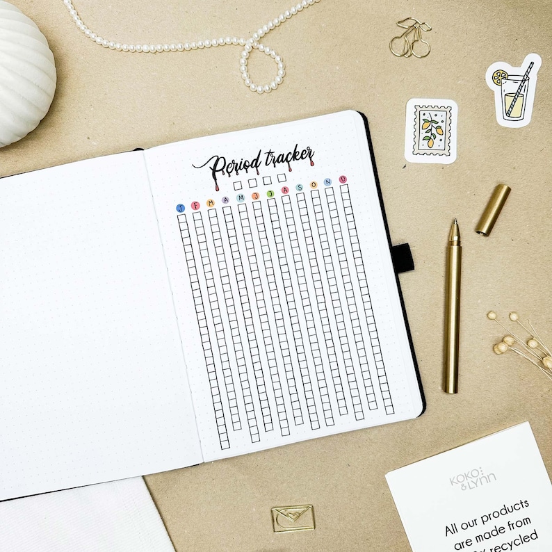 May include: A white and black period tracker with a grid of squares for each day of the year. The months are labelled at the top: January, February, March, April, May, June, July, August, September, October, November, December. The words "Period Tracker" are written in black cursive at the top of the page.