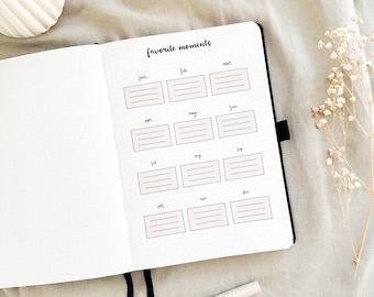 May include: A black and white planner with the words "favorite moments" written at the top. The planner has a grid layout with spaces for each month of the year.