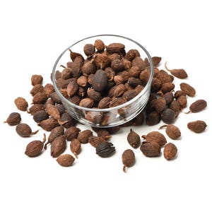 May include: A clear glass bowl filled with numerous dried black cardamom pods, with additional pods scattered around the base of the bowl. The pods are dark brown, oval-shaped, and feature a distinctively wrinkled, fibrous outer texture.