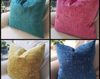 May include: Four decorative throw pillows with a textured fabric. The pillows are in four different colors: teal, pink, yellow, and blue.
