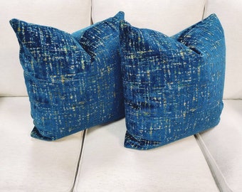 May include: Two blue throw pillows with a gold and white abstract pattern. The pillows are made of a soft, velvet-like fabric.