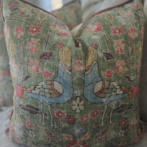 May include: Two green throw pillows with a floral pattern and stylized birds in blue, yellow, and red.