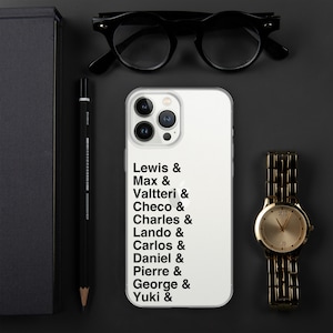 May include: White phone case with a list of names and the word "&" after each name: Lewis, Max, Valtteri, Checo, Charles, Lando, Carlos, Daniel, Pierre, George, Yuki.