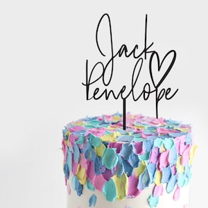 Peut inclure: Topper de gâteau en acrylique noir avec les noms "Jack" et "Penelope" écrits en cursive avec un symbole de cœur entre les noms.