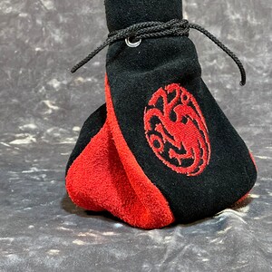 May include: A black and red suede drawstring bag with a red embroidered dragon design.
