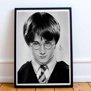 Puede incluir: Retrato en blanco y negro de una persona joven con gafas redondas, una camisa blanca con cuello y una corbata a rayas. El retrato está enmarcado en un marco negro y se muestra sobre un suelo de madera.