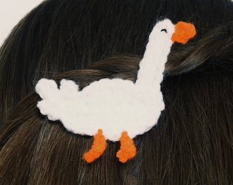 May include: A white crocheted goose hair clip with orange beak and feet.