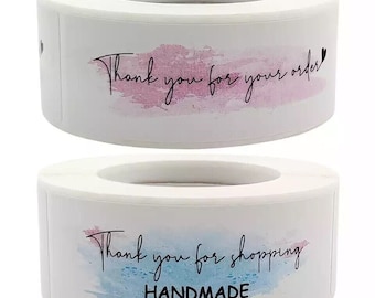 Op de afbeelding: Twee ronde witte stickers met een aquarelontwerp. De bovenste sticker heeft een roze aquarelontwerp en de tekst "Bedankt voor uw bestelling". De onderste sticker heeft een blauw aquarelontwerp en de tekst "Bedankt voor uw aankoop HANDGEMAAKT".