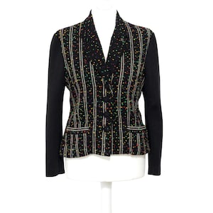 Op de afbeelding: Een zwarte blazer met een gestreept patroon en kleurrijke vlekken. De blazer heeft zwarte mouwen, een reverskraag en twee voorzakken. Het wordt gepresenteerd op een witte mannequin.