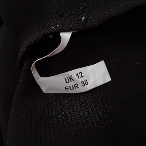 Może przedstawiać: Biała metka z czarnym tekstem wskazująca rozmiar odzieży: UK 12 EUR 38.
