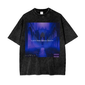 Puede incluir: Camiseta negra con un aspecto descolorido que presenta un gráfico del interior de una iglesia con el texto "LUCK INBETWEEN DEATH" y el nombre del artista "PRYER" en morado. También se incluye el texto "Parental Advisory Explicit Content".