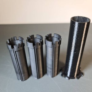 以下が含まれることがあります： 装飾的なトップが付いた黒いプラスチック製の円筒が4つと、装飾的なトップとボトムが付いた大きな黒い円筒が1つあります。