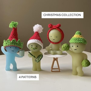 May include: A collection of four figurines, each with a unique Christmas-themed crochet hat. The figurines are in various poses, with one holding a small cup and another holding a small table. The text "CHRISTMAS COLLECTION" and "4 PATTERNS" are visible.