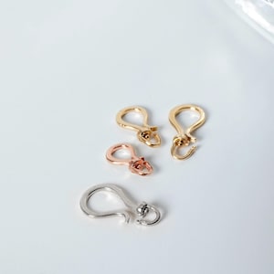 K&ouml;nnte beinhalten: Drei Metall-Hummerverschl&uuml;sse in verschiedenen Gr&ouml;&szlig;en. Die Verschl&uuml;sse sind in Gold, Ros&eacute;gold und Silber.