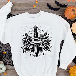 May include: White sweatshirt with a black and white graphic print of a dagger with flowers and the text "I WILL NOT DIE TODAY".